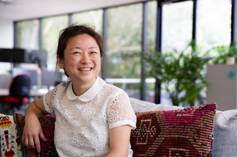 A person sitting in a cafe smiling at the camera.