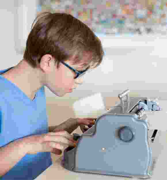 A young child using a braille machine.