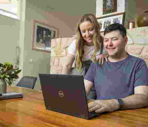 Two people looking at a laptop on a table