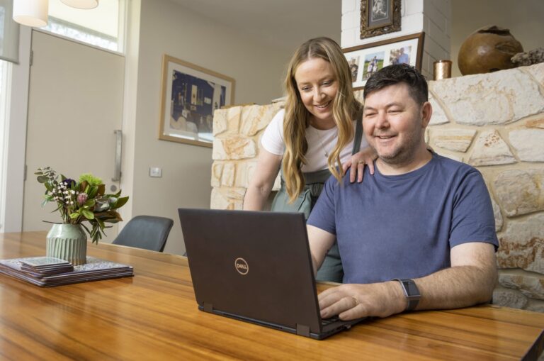 Two people looking at a laptop on a table