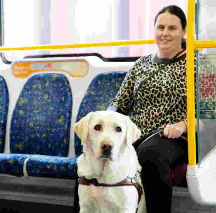 A white cane user walks past the baggage X-ray machine at airport security.