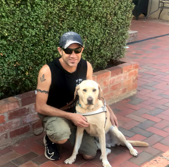 Steve kneels down next to his Guide Dog Heath