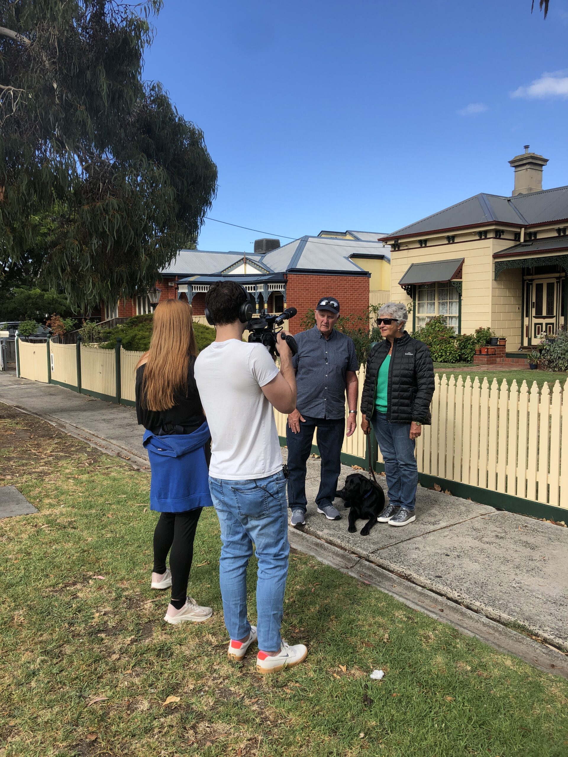 Two people filming outside a house