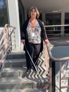 A person with a long cane walking down a set of stairs.