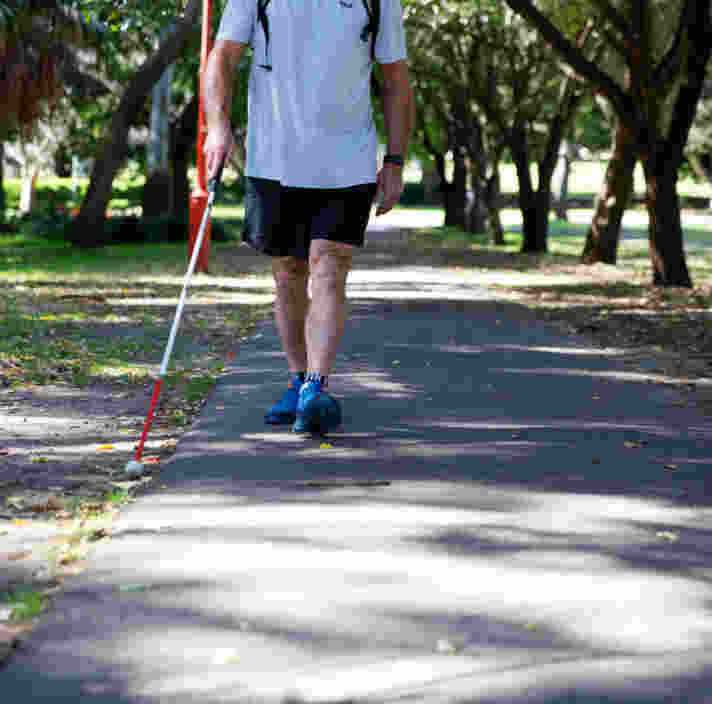 A person walking with a long white cane.