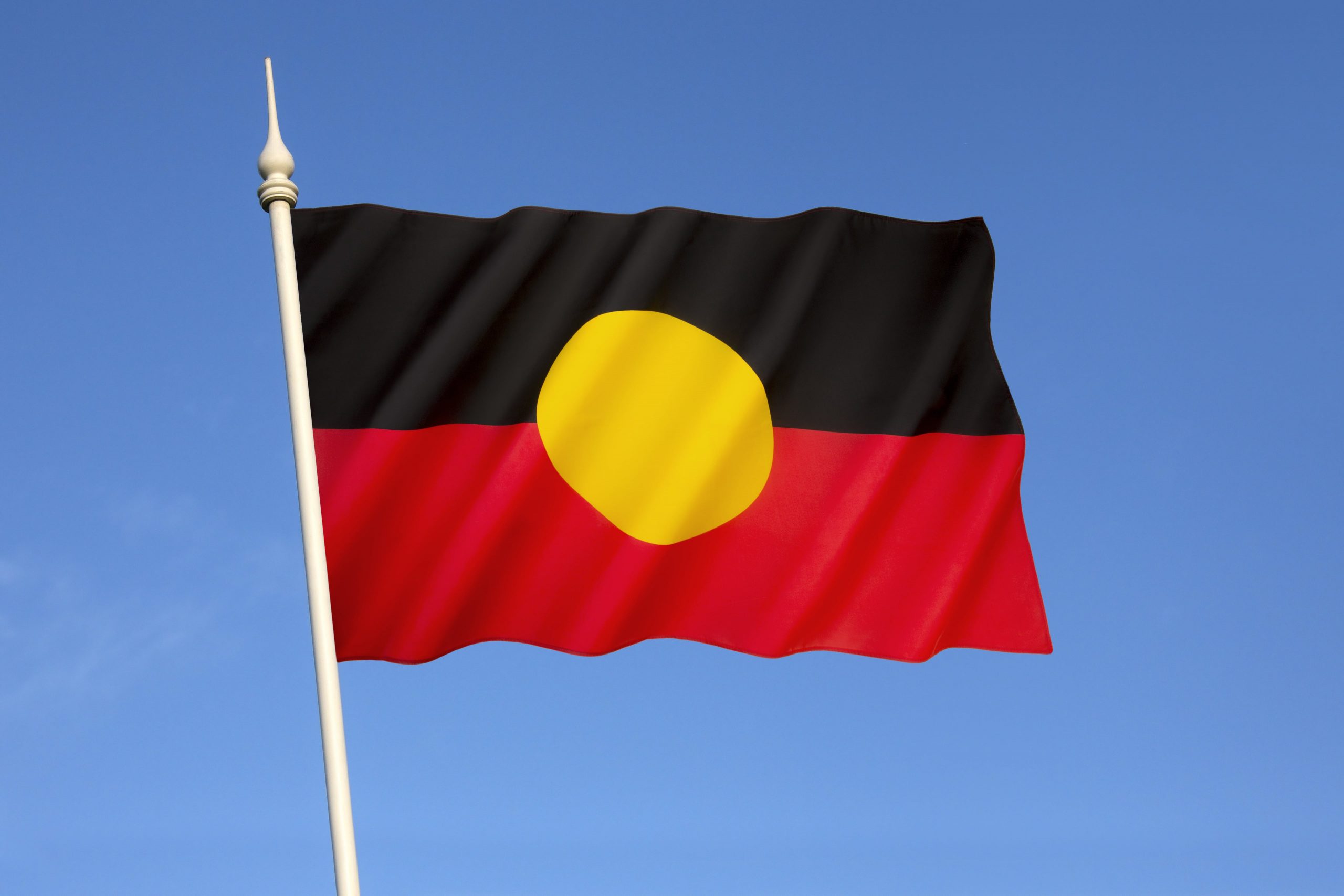 The Australian Aboriginal flag waving against a blue sky