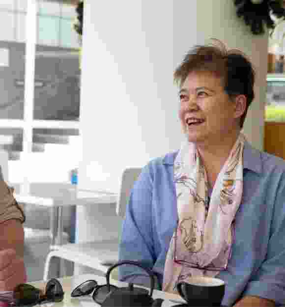 Two people sitting at a cafe smiling at each other.