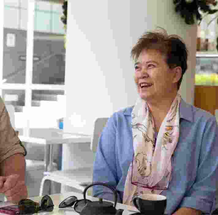 Two people sitting at a cafe smiling at each other.