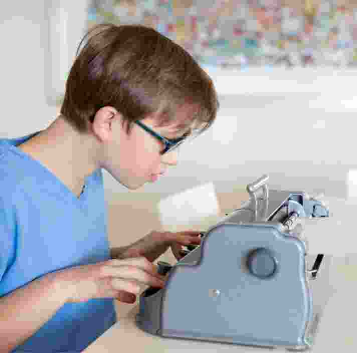 A young child using a braille machine.