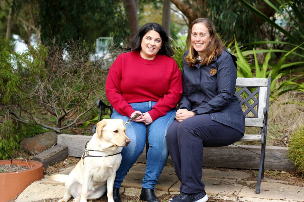 A Guide Dogs staff member sits next to a Client and their Guide Dog