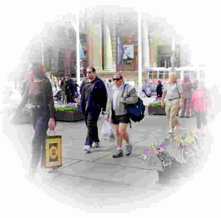 A busy footpath with people on it. The outer edges of the image is blurred with a white circle to portray how someone with Glaucoma might view it.