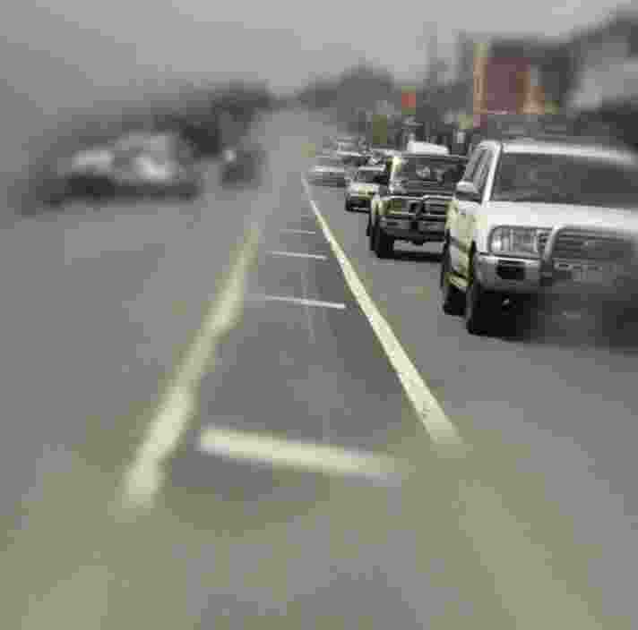 A busy road with cars on it. The outer edges of the image are blurred to portray how someone with retinitis pigmentosa might view it.