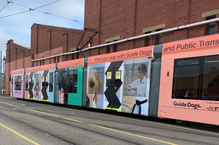 A tram wrapped in the new Guide Dogs branding with high contrast shapes on the doors and images of people and dogs