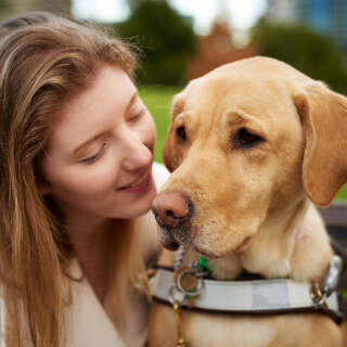 A woman pictured with a Guide Dog in harness.