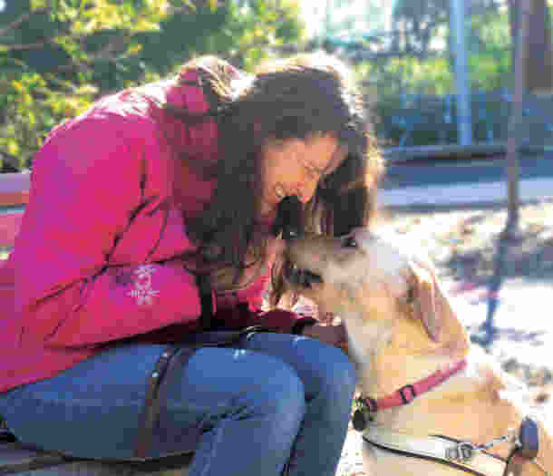 Melaine sits on a park bench and holds her face close to Dessau's