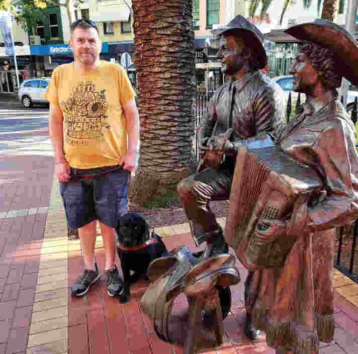 Murray standing next to his seated Guide Dog, Karli