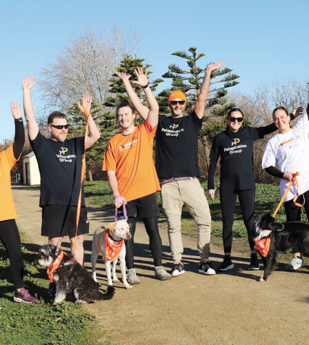 a group of people raising their hands in the air while holding dogs on leads.