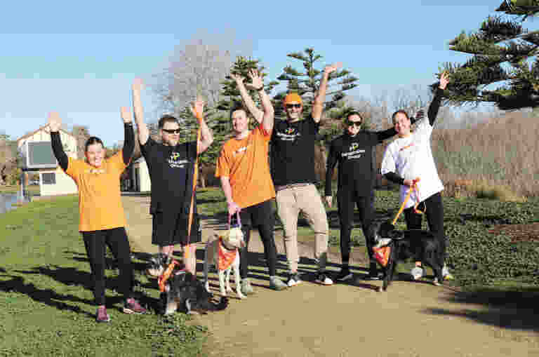 a group of people raising their hands in the air while holding dogs on leads.