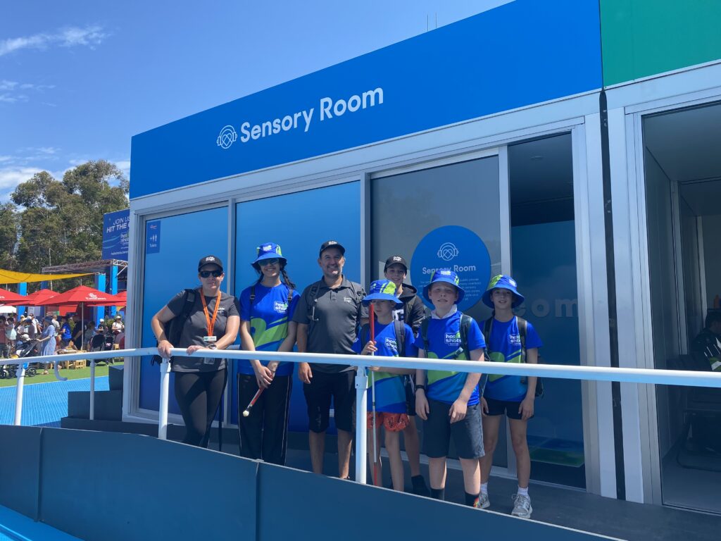 A group of seven adults and children standing outside the Sensory Room at the AO. 