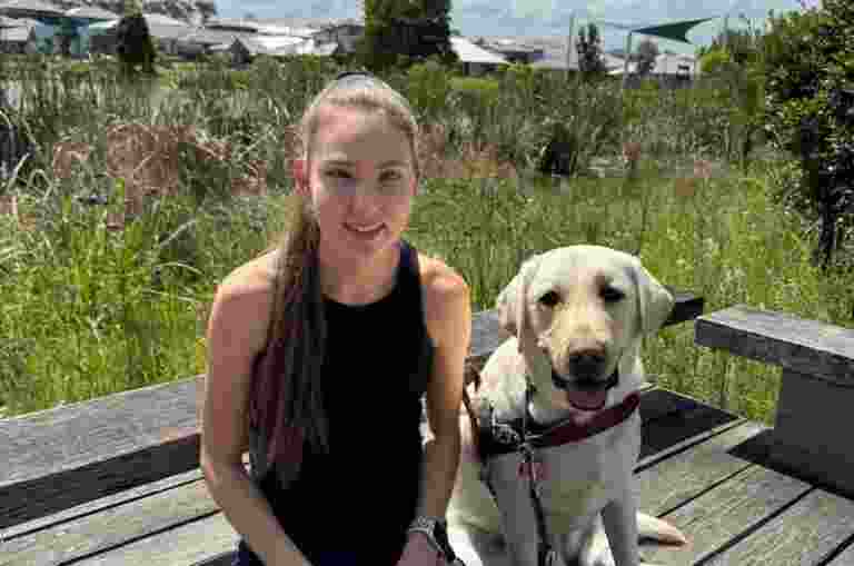 Karlee sitting next to her Guide Dog, Isla