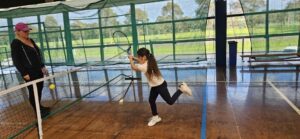 A camp member and coach playing Blind Tennis on an indoor tennis court.