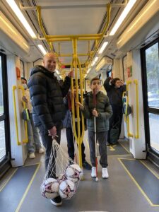 A Guide Dogs Victoria staff member and two Clients travelling on a tram to a sports field.