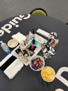 Makeup, tools and snacks set up on the table. 