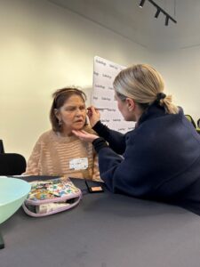 A Client being supported by Stacey on how to apply makeup.