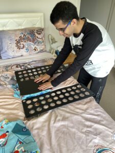 Matt stands in front of a bed using a folding board placed on the bed to easily and efficiently fold his clothes.