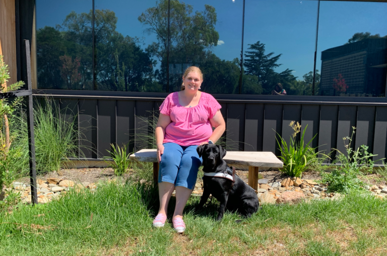 Tegan sitting with Ethel in Guide Dogs Victoria's sensory garden.