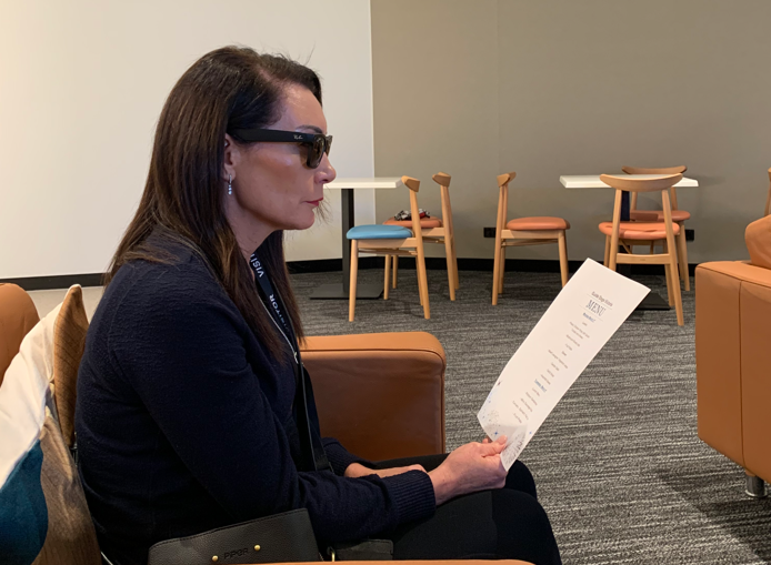 A woman wearing the Meta glasses tries to get it to read a piece of paper at reading length.