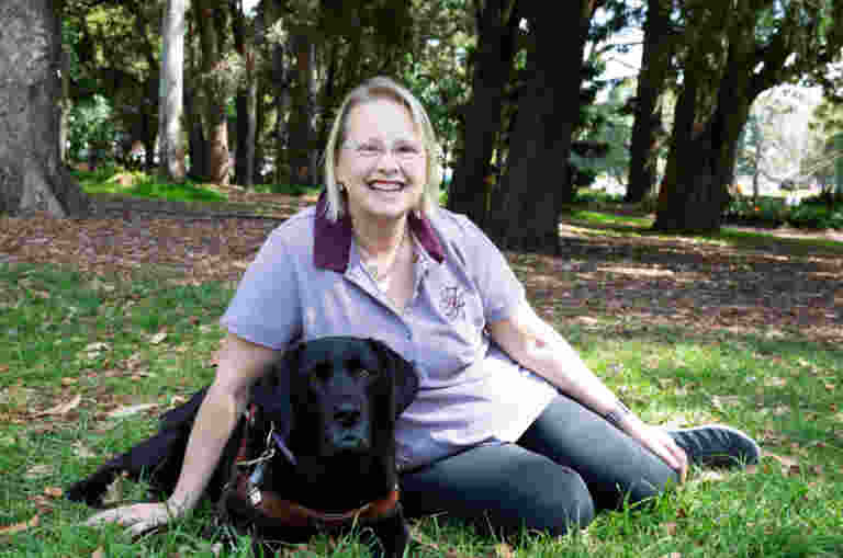 A person and their Guide Dog sitting together at a park.