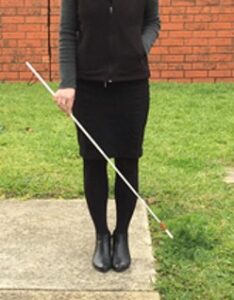 A person using holding a white ID cane.