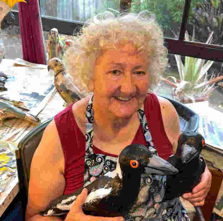 Jane in her studio holding two of her magpie sculptures.