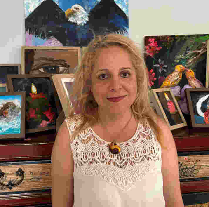 Sara standing in front of a mantle which has a number of her art pieces on display.