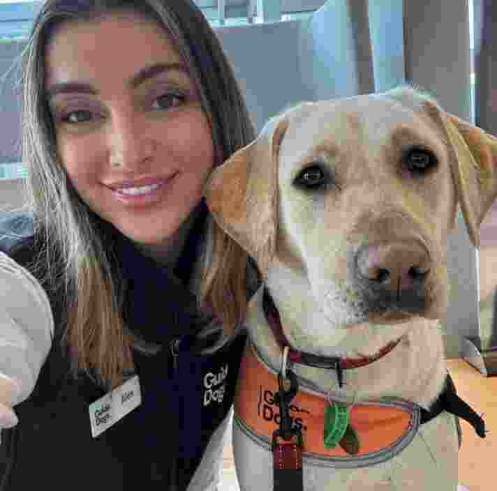 Alex smiling at camera with yellow lab next to her also looking at the camera.