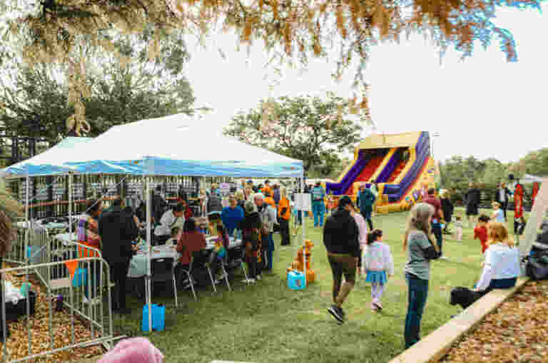 Kids Zone at the Guide Dogs Community Fair. Stalls with activities and a big blow up slide are set up on the grass.