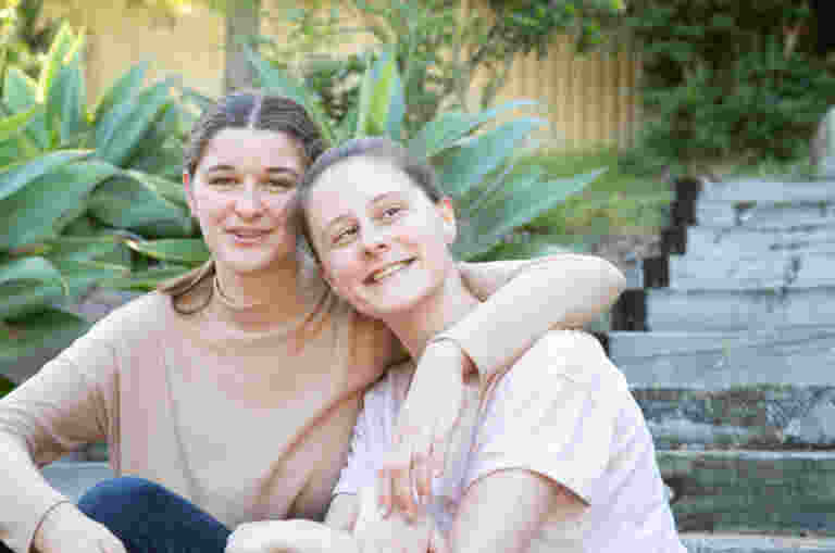 Two teenage girls smiling at the camera.