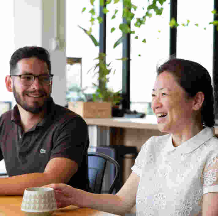 A man and a woman sitting at a dining table in a kitchen having a cup of tea.