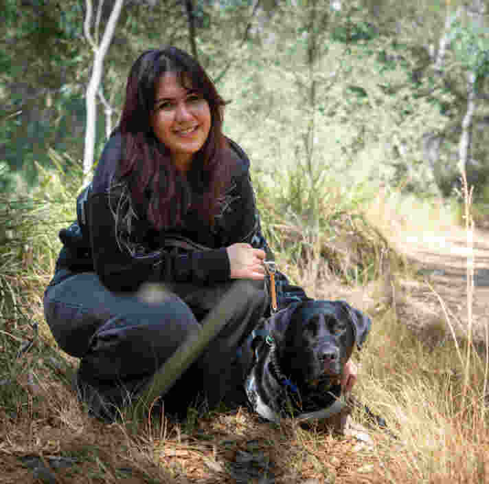 Maysoun crouched down beside her Guide Dog.