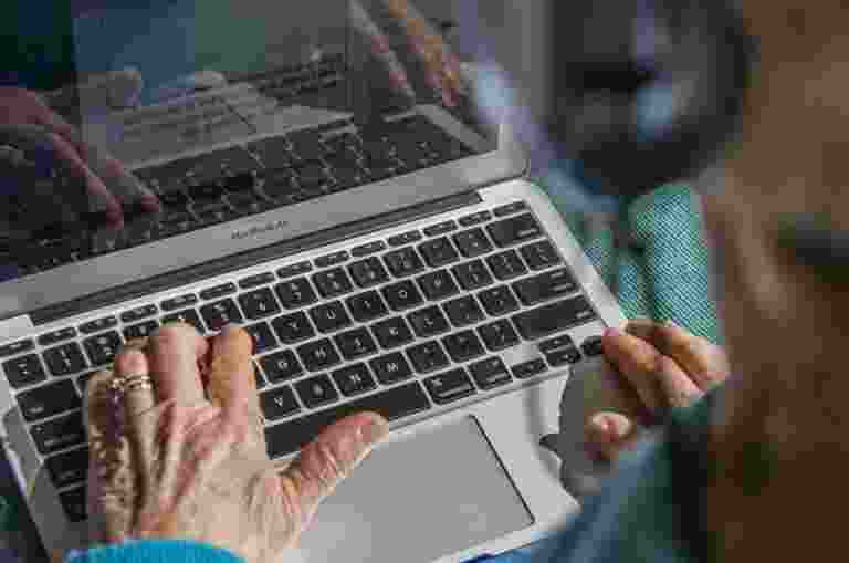 Someone typing on a computer wearing headphones