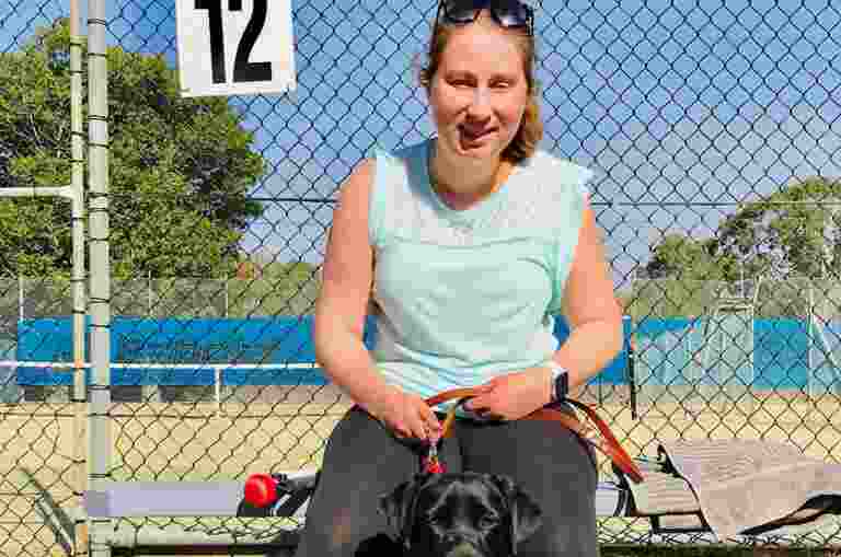 Emily sitting with a black Guide Dog