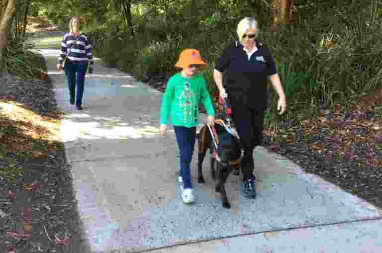 Young client walking with a Guide Dog beside an instructor