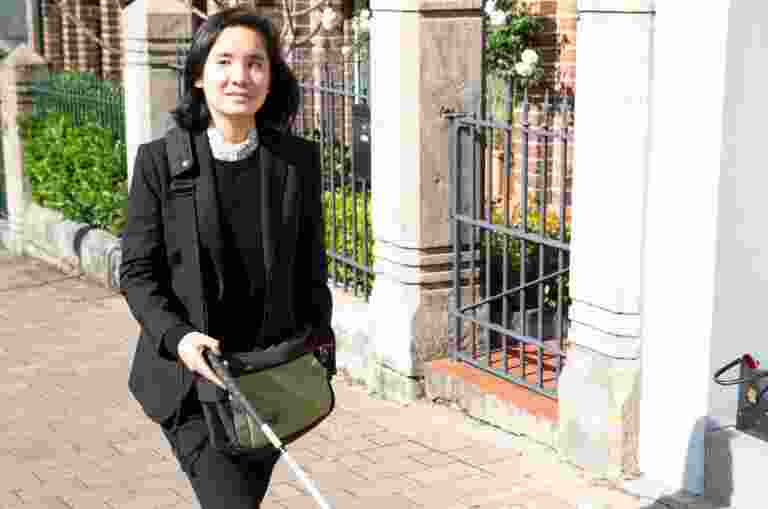 Lady with low vision or blindness, walking outside using a long cane for guidance