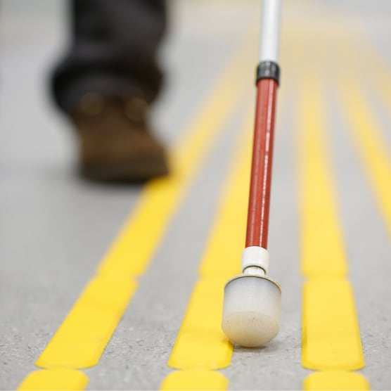 A White Tip cane on yellow tactile paving