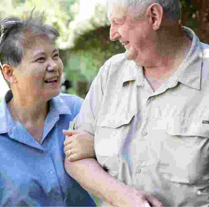Two people outside looking at each other. One is holding the other at the elbow.
