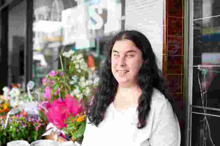 A person standing outside a flower shop with a smile on their face.