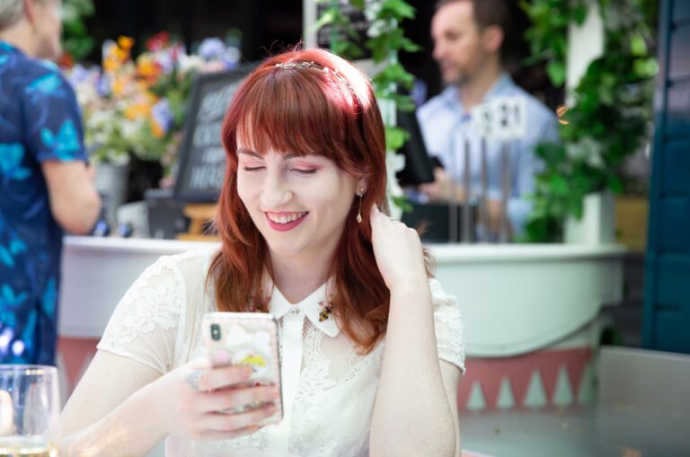 A person sitting at a cafe looking at their phone smiling.