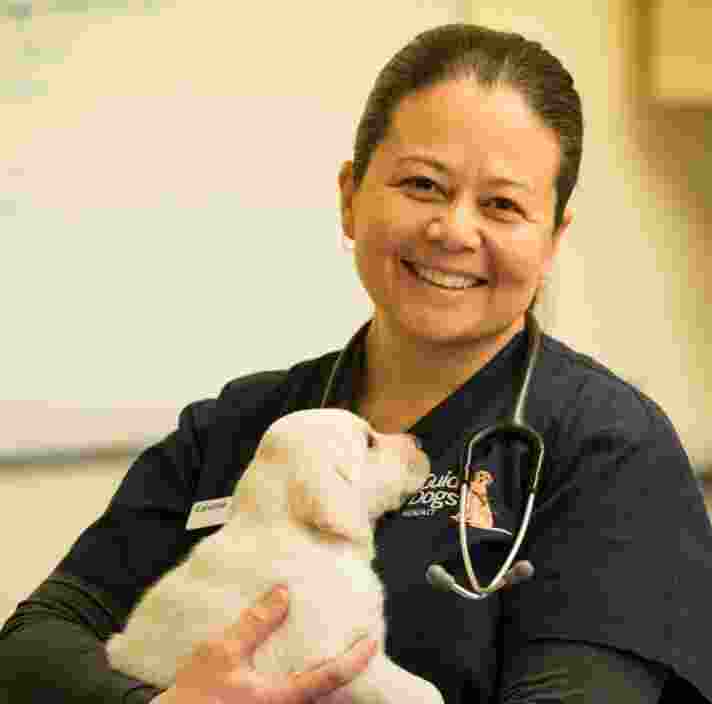 Caroline Moeser smiling while holding a labrador puppy