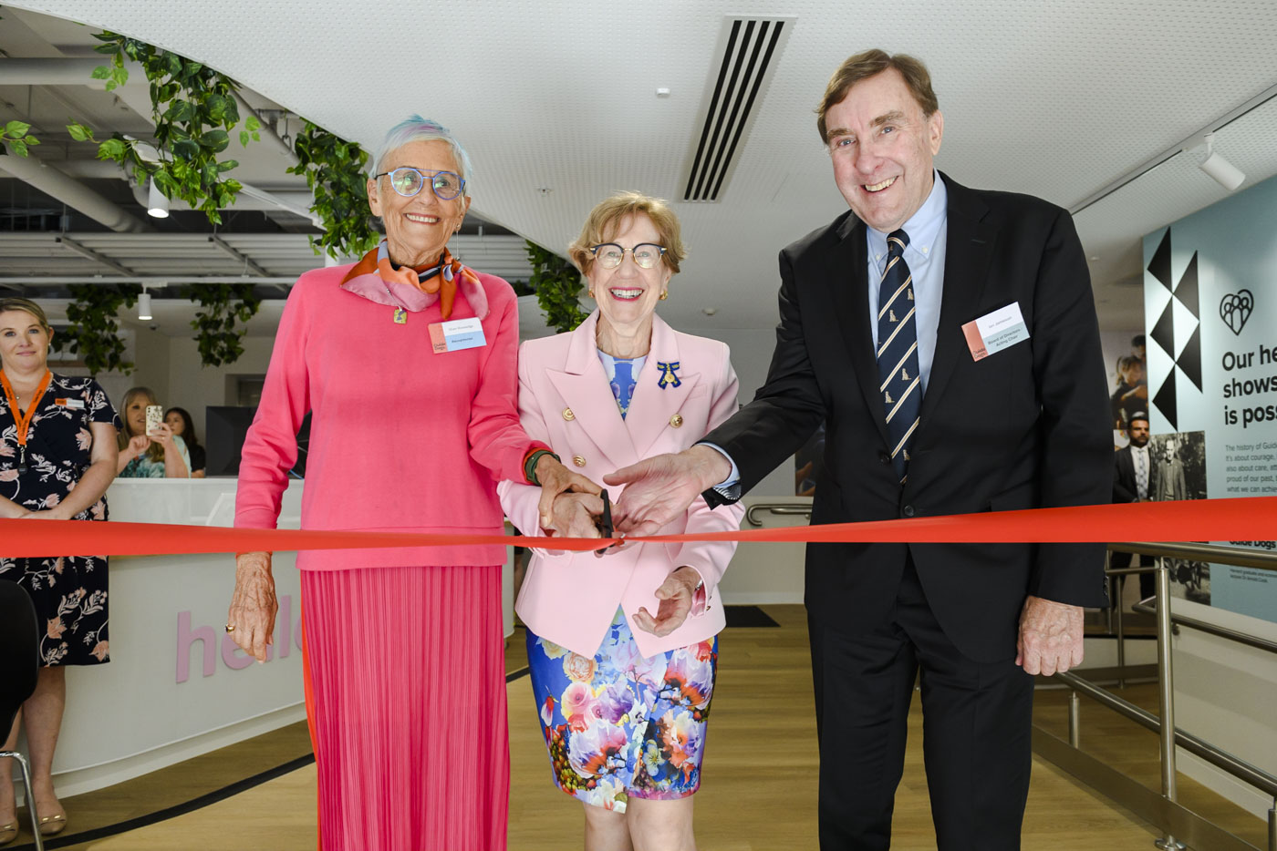 Three people cutting a ribbon to open a new office.
